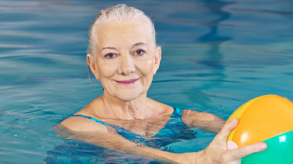senior woman with water ball in pool senior woman with water ball in pool